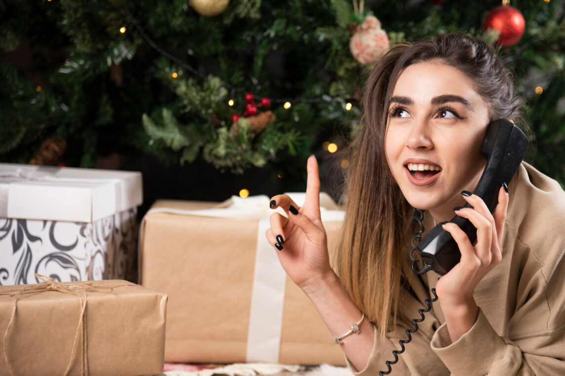 Kobieta rozmawiająca przez telefon przed choinką