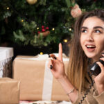 Kobieta rozmawiająca przez telefon przed choinką